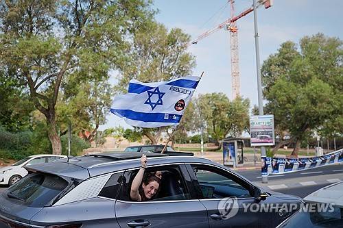 27일 이스라엘 총선이 치러지는 가운데, 텔아비브의 거리에서 한 여성이 차창 밖으로 이스라엘 국기를 흔들고 있다. [AP 연합뉴스. 재판매 및 DB 금지]