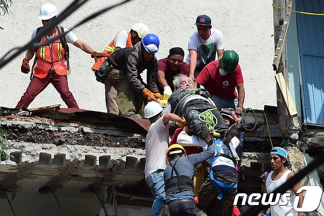 건물에 매몰돼있던 생존자를 구출해내는 구조대. © AFP=뉴스1