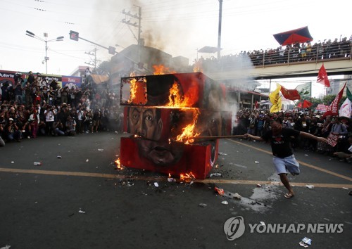 필리핀 마닐라에서 21일 시위대가 마르코스 전 대통령과 두테르테 현 대통령 사진을 불태우고 있다.[EPA=연합뉴스]