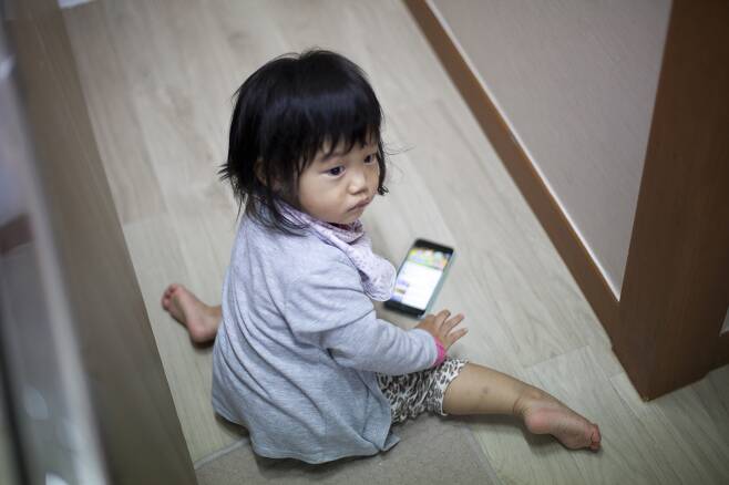 장하나 전 의원의 딸 두리가 엄마 휴대폰을 가지고 놀고 있다. 육아정책연구소가 2014년에 연구한 조사에 따르면, 우리나라 영유아들이 처음으로 스마트폰을 접하는 나이가 0.84살인 것으로 나타났다. 두리 아빠 사진가 점좀빼