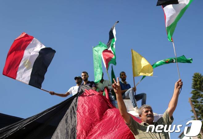 팔레스타인 주민들이 12일(현지시간) 이집트와 팔레스타인·파타·하마스를 상징하는 깃발을 흔들며 통합합의문에 환호하고 있다. © AFP=뉴스1