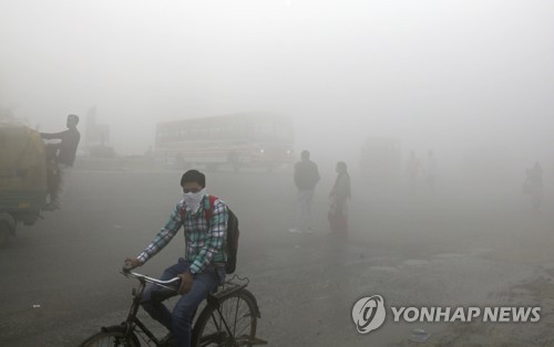 10일 인도 뉴델리 외곽에서 짙은 스모그가 낀 거리를 한 남성이 손수건을 얼굴에 두른 채 자전거를 타고 지나가고 있다.[AP=연합뉴스 자료사진]