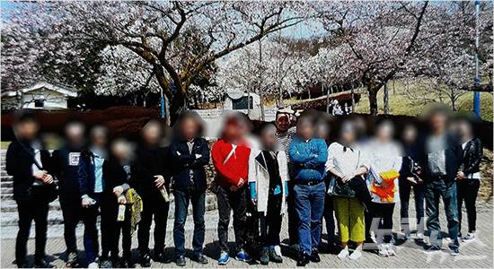 2016년 3월 31일~4월 2일. 동아대 미술학과 야외스케치 당시 교강사 및 조교들 단체사진. 가운데 햇빛을 가리고 있는 고 손현욱 교수와 청색 옷을 입고 있는 A교수.
