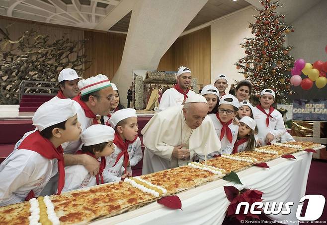 17일(현지시간) 81번째 생일을 맞은 프란치스코 교황이 아이들과 함께 피자에 꽂힌 촛불을 불고 있다. © AFP=뉴스1