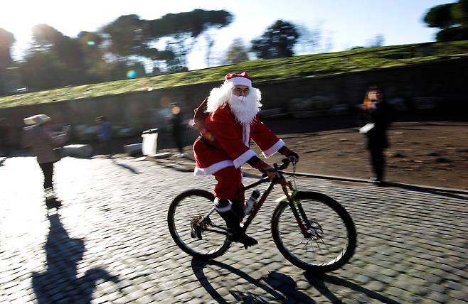 17일(현지시간) 이탈리아 로마에서 산타 복장을 한 시민이 자전거를 타고 이동하고 있다.[로이터=연합뉴스]