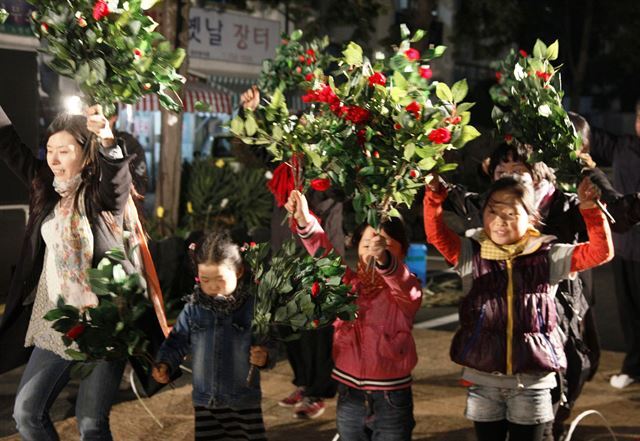 4.3문화예술축전에서 참가자들이 동백꽃 가지를 흔들고 있다.