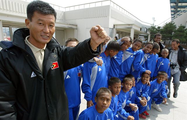 2004년 3월 일본 히로시마에서 열린 '제30회 리베리노컵 국제축구대회'에 출전한 동티모르 유소년 대표팀과 김신환(맨 왼쪽) 감독이 경기 전 ‘파이팅’을 외치고 있다. 연합뉴스