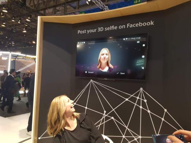 소니의 신규 스마트폰 ‘엑스페리아XZ2’에 탑재된 3D 포토 기능을 체험한 관람객이 3D로 구현된 자신의 모습을 보고 환하게 웃고 있다.