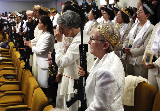 지난달 28일 미국 펜실베이니아주 뉴파운드랜드에 있는 '세계평화통일안식처’ 교회에서 열린 합동결혼식 참석자들의 모습. 머리에 왕관을 쓴 참석자들의 손에 AR-15 소총이 들려 있다. [AP=연합뉴스]