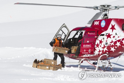 올해 1월 에어체르마트 헬리콥터 직원이 산사태 위험 지역에서 인공 눈사태를 일으켜 눈을 제거하기 위한 폭발물을 헬리콥터에 싣고 있다. [EPA=연합뉴스]