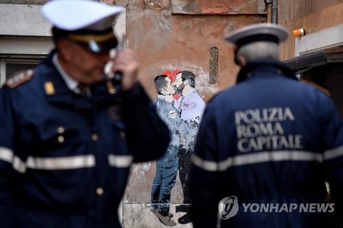 23일 로마 중심가에 루이지 디 마이오 오성운동 대표와 마테오 살비니 동맹 대표의 키스 장면을 그린 벽화가 등장했다. 경찰이 그림 앞에 서성이고 있다. [AFP=연합뉴스]