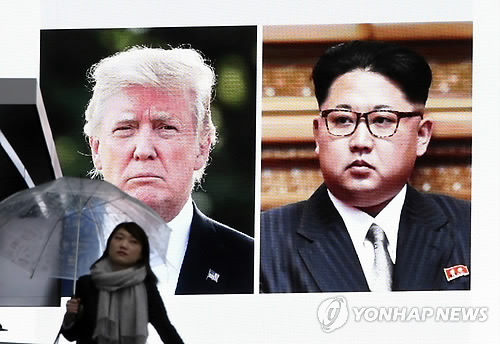 일본 도쿄에서 한 여성이 트럼프 미국 대통령과 북한 김정은의 얼굴을 띄운 대형 스크린 앞을 지나는 모습[AP=연합뉴스 자료사진]