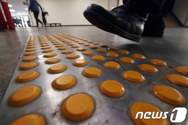 17일 오후 광주 서구 염주체육관에 설치된 점자블록 위로 한 시민이 지나가고 있다.018.4.17/뉴스1 © News1 남성진 기자