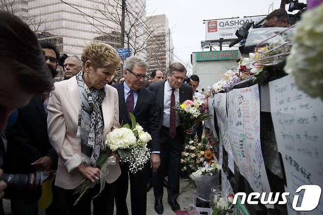 토론토 밴 사고 현장에 세워진 추모의 벽에 헌화하고 있는 시민들. <자료사진> © AFP=뉴스1