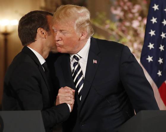 트럼프 대통령과 마크롱 대통령이 손을 잡은 채 볼을 맞대는 프랑스식 '비주' 인사를 나누고 있다. [EPA=연합뉴스]