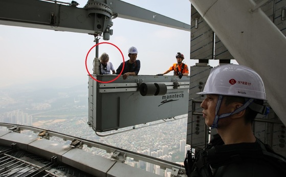 서울 송파구 롯데월드타워 외벽을 맨손으로 오르던 프랑스인 등반가 알랭 로베르(56)가 건물에 설치된 곤돌라를 타고 126층 옥상으로 올라오고 있다. [롯데물산 제공]