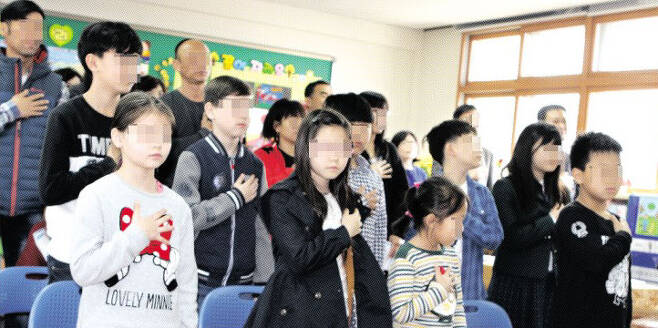 지난해 4월 충남 모 초등학교 예비학교 입학식에서 중도입학 외국인 학생들이 손을 가슴에 얹고 국기에 대한 경례를 하고 있다. 충남도교육청 제공