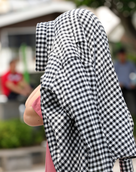전북 전주시 풍남문 광장에서 한 시민이 자외선을 피하기 위해 옷으로 얼굴 등을 가리며 길을 걷고 있다. [뉴스1]