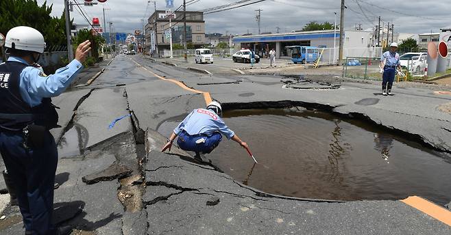18일 오사카 현 다카쓰키시에서 발생한 지진으로 인한 도로 파손 사고를 점검하고 있다. [EPA=연합뉴스]