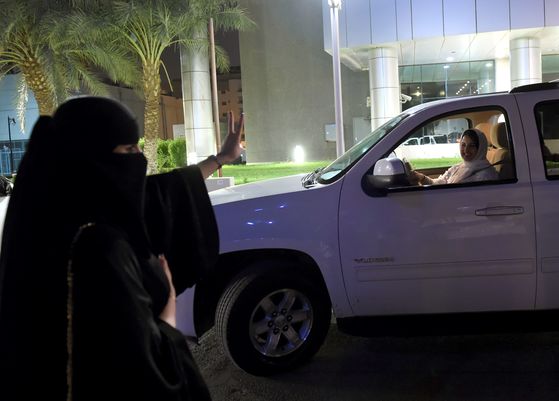 한 사우디 여성이 24일(현지시간) 리다아 중심 도로에서 운전하는 사마르 알 모겐에게 손으로 'V' 표시를 하며 응원하고 있다. [AFP=연합뉴스]