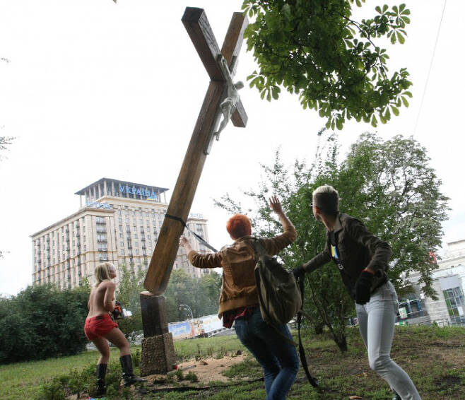 예수가 매달린 나무십자가를 전기톱으로 잘라버린 페멘의 리더 인나 셰브첸코. 이 일로 그는 나고 자란 우크라이나를 떠나 프랑스에 정착했다. 페멘 홈페이지