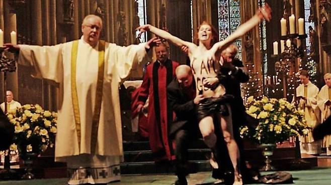 쾰른 대성당에서 열린 성탄미사에 난입한 페멘 활동가를 교회 관계자들이 제지하고 있다.