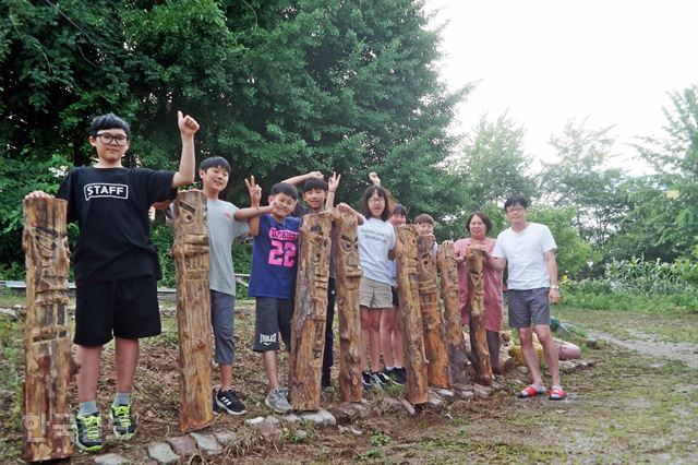 한 주 전 직접 나무를 깎아 만든 장승을 든 아이들이 활짝 웃고 있다. 맨 오른쪽이 양성주 센터장과 임성훈 사무장 부부. 임실=김혜영기자