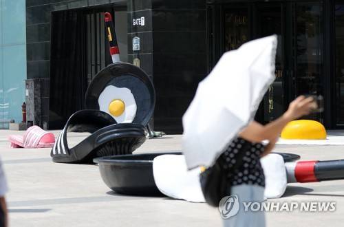 매일 뜨거운 날의 연속 (대구=연합뉴스) 김준범 기자 = 찜통더위가 이어진 23일 오후 현대백화점 대구점 앞에서 시민들이 더위에 익은 달걀프라이와 녹아내린 슬리퍼 조형물 사이를 지나가고 있다. 2018.7.23 psykims@yna.co.kr