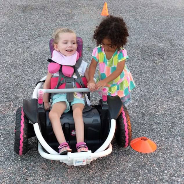 애비가 단짝 루비의 손을 전동 휠체어 위에 올려주고 있다.