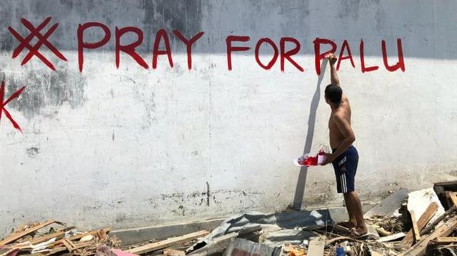 한 남성이 최근 강진과 쓰나미 피해를 입은 인도네시아 팔루를 위해 기도해달라는 문구를 쓰고 있다.BBC 캡처
