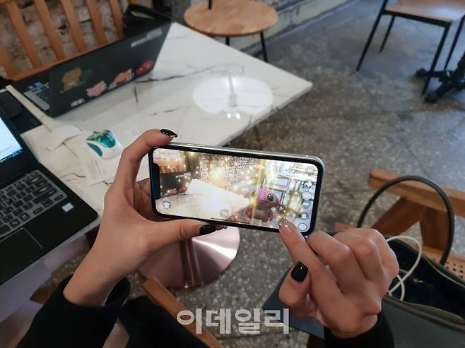 아이폰XR로 AR 애완동물 육성 게임을 하는 모습.