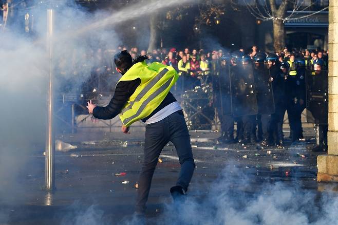 17일(현지시간) 프랑스 전역에서 정부의 유류세 인상 조처에 항의하는 대규모 시위가 발생한 가운데 서부 캥페르의 한 거리에서 노란색 야광 조끼를 입은 한 시위 참가자가 경찰을 향해 무언가를 던지고 있다. /AFPBBNews=뉴스1