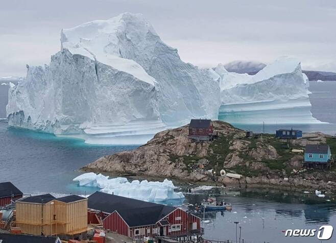그린란드 북서부 아바나타 시 이나루트 마을 외곽 집과 건물들 뒤에 있는 빙산.  © AFP=뉴스1