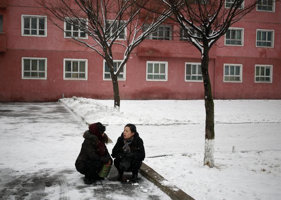 평양 시내에 16일 눈이 내렸다. 두 여인이 거리에 쪼그리고 앉아 대화하고 있다. [AP=연합뉴스]