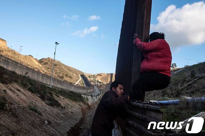 지난달 27일(현지시간) 중미 이민자 2명이 멕시코 티후아나와 미국 샌디에이고 국경지대를 넘고 있다. © AFP=뉴스1