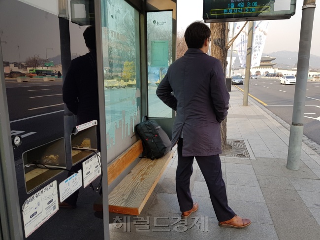 태양광 휴대폰 유무선 충전기가 마련된 버스정류장에서 시민이 버스를 기다리고 있다. [성기윤 기자/skysung@heraldcorp.com]