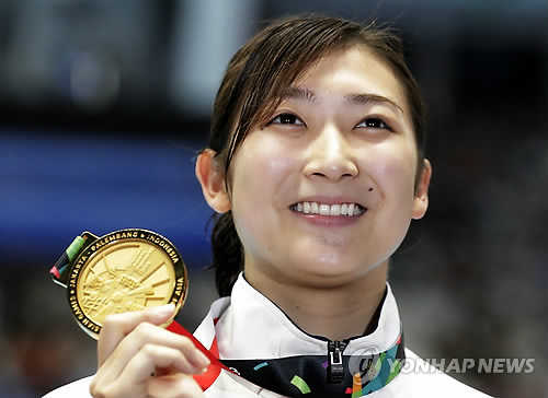 일본을 대표하는 여성 수영선수인 이케에 리카코가 지난해 8월 24일(현지시간) 인도네시아 자카르타에서 열린 제18회 아시안게임 여자 50m 자유형에서 우승한 뒤 시상대에 올라 금메달을 들어 보이고 있다. [AP=연합뉴스 자료사진]
