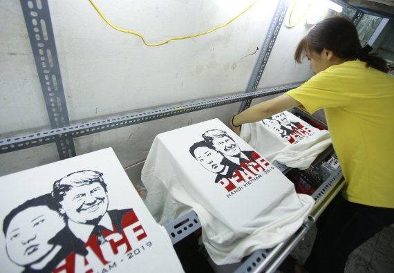 21일 베트남 하노이에서 한 티셔츠 매장 직원이 도널드 트럼프 미국 대통령과 김정은 북한 국무위원장의 2차 정상회담을 기념하는 티셔츠를 손질하고 있다.AP연합뉴스