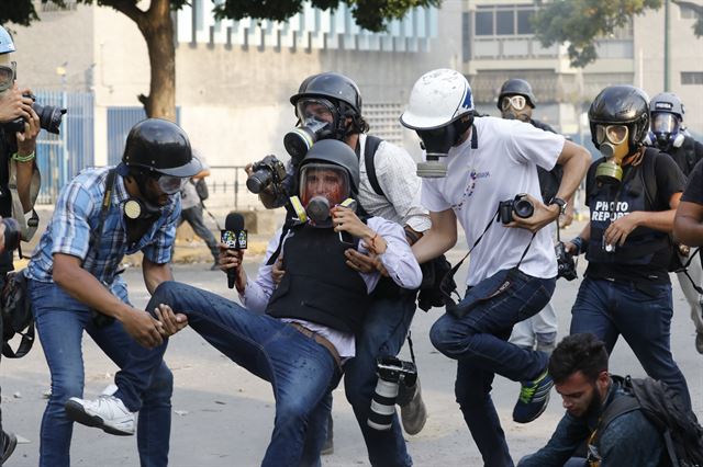 1일 니콜라스 마두로 베네수엘라 대통령에 저항하는 대규모 시위가 벌어진 카라카스 시내에서 취재하던 기자 한 명이 총상을 입고 동료에 의해 옮겨지고 있다. 카라카스=AP 연합뉴스