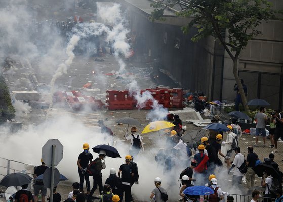 지난 12일(현지시간) 홍콩 의회 격인 입법회 건물 주변에서 범죄인 인도법에 반대하는 시위대가 경찰이 발사한 최루가스를 피해 달아나고 있다. [AP=연합뉴스]
