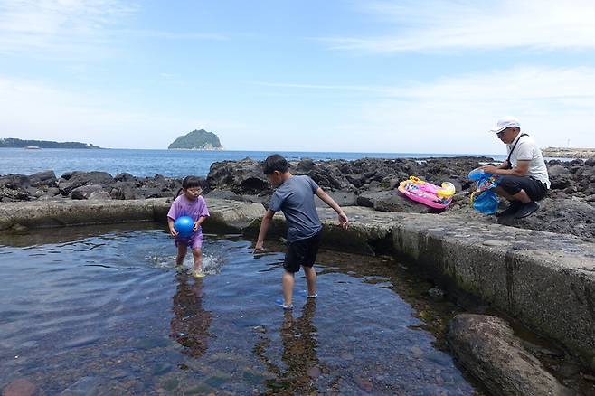 용천수가 솟아나는 서귀동 자구리 해안에서 물놀이에 열중하는 김유천(7)·유주(5) 남매. 뒤쪽에는 섶섬(숲섬)이 솟아 있다. 사진 송호균 제공