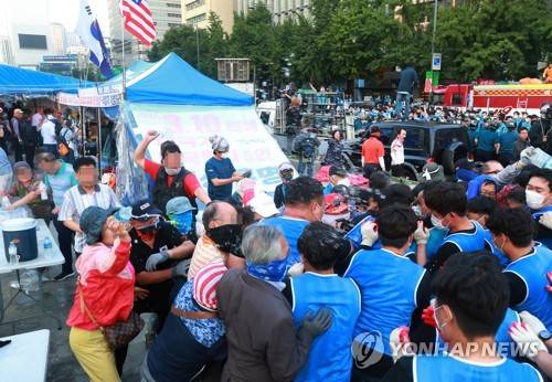 거센 저항 속에서 행정대집행 (서울=연합뉴스) 홍해인 기자 = 25일 오전 서울 종로구 광화문 광장에서 농성 중이던 대한애국당(우리공화당) 천막을 서울시와 용역업체 관계자들이 철거 작업에 돌입하자 당원들이 물을 뿌리고 몸싸움을 벌이며 저항하고 있다. 서울시는 오전 5시 20분부터 천막 2동 등 불법 설치물에 대한 행정대집행을 실시 중이다. 대한애국당은 24일 당명을 '우리공화당'으로 개정했다. 2019.6.25 hihong@yna.co.kr