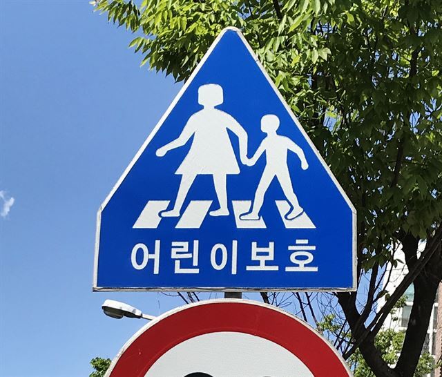 경기 고양시의 한 초등학교 앞 횡단보도 부근에 ‘어린이 보호’ 표지판이 세워져 있다. 도로교통법에 따라 표지판 속 보호자는 여성으로 표현돼 있다.