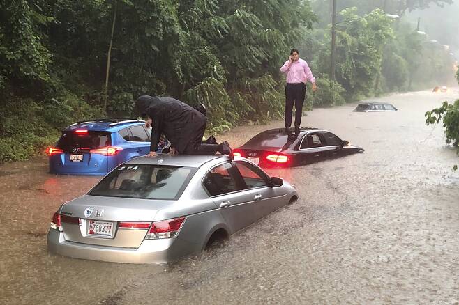 워싱턴의 한 도로에 폭우로 침수된 차량 위에 운전자들이 대피해 있다. [AP=연합뉴스]