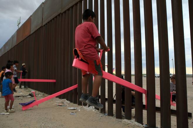 높은 철제 울타리로 막혀 있던 미국과 멕시코 국경에 분홍색 시소가 생겼다./사진=AFP