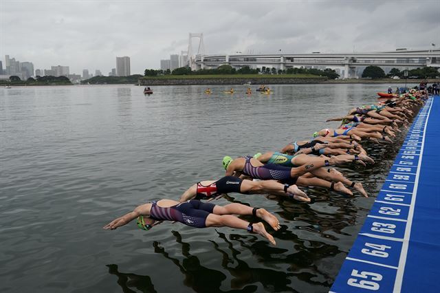 15일 도쿄 오다이바해변공원에서 열린 트라이애슬론 대회 중 오픈수영경기에 참가한 선수들이 바다로 뛰어들고 있다. 도쿄=AP 연합뉴스