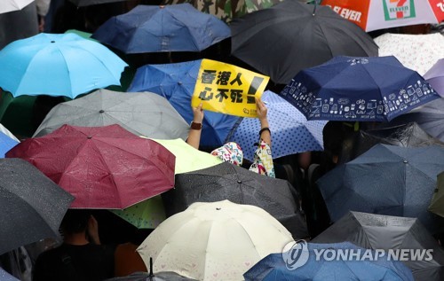 중국 무력진압 우려 속에 열린 홍콩 대규모 집회 (홍콩=연합뉴스) 김주성 기자 = 18일 오후(현지시간) 홍콩 빅토리아 공원에서 송환법에 반대하고 경찰의 강경 진압을 규탄하는 대규모 도심 집회에 참가한 한 홍콩 시민이 우산행렬 사이로 손팻말을 들고 있다.       이날 집회는 홍콩 대규모 도심 시위를 주도했던 민간인권전선 주도로 열렸다. 2019.8.18 utzza@yna.co.kr