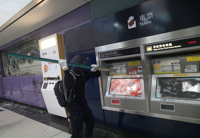 홍콩 시위 참가자가 1일 공항과 인접한 퉁청역에서 쇠파이프로 자동판매기를 후려치고 있다. EPA 연합뉴스