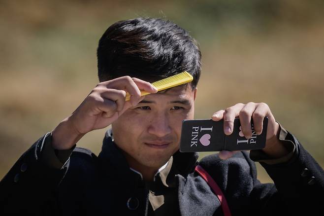 지난 11일 백두산 천지를 방문한 한 북한 학생이 친구들과 물장난을 한 후 머리를 빗고 있다. "나는 핑크를 좋아한다"는 영문이 눈에 띈다. [AFP=연합뉴스]