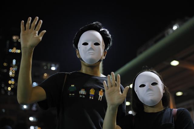 홍콩 정부의 복면금지법 시행 방침을 비웃기라도 하듯 5일 거리 시위에 나선 시민들이 마스크를 쓴 채 손을 들어 보이고 있다. 손가락 다섯 개는 시위대가 정부에 요구하는 5대 방안을 뜻한다. 홍콩=AP 연합뉴스
